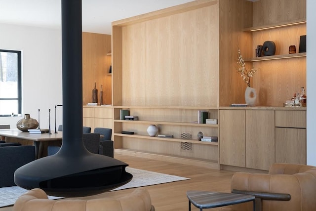 interior space with built in shelves, wood finished floors, and a wood stove