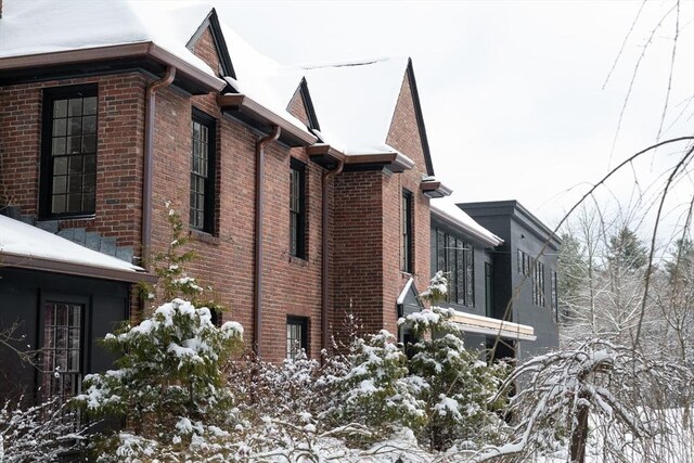 snow covered property with brick siding