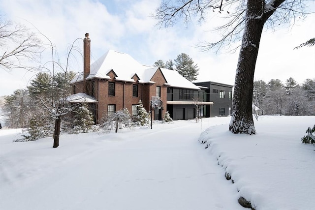 snow covered house with a garage and a chimney