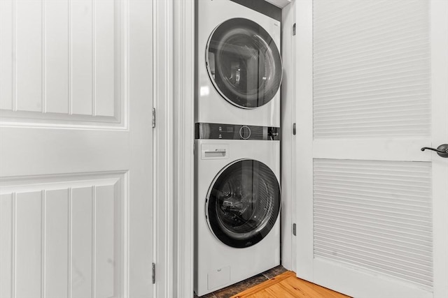 laundry room with laundry area, stacked washer / dryer, and wood finished floors