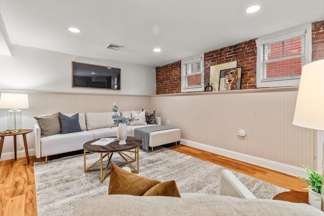 living area with a wainscoted wall, wood finished floors, visible vents, and recessed lighting