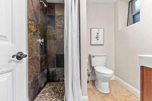 bathroom featuring toilet, baseboards, a tile shower, and tile patterned floors