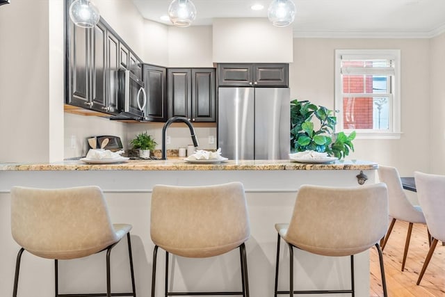 kitchen featuring a peninsula, stainless steel appliances, crown molding, and a kitchen breakfast bar