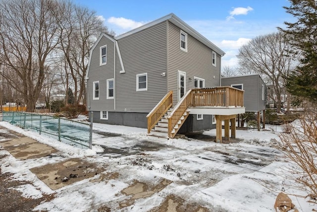 snow covered house with a wooden deck