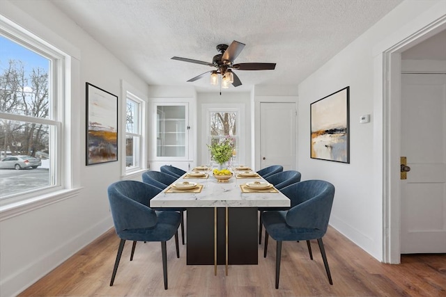 dining area with ceiling fan, hardwood / wood-style floors, and a textured ceiling