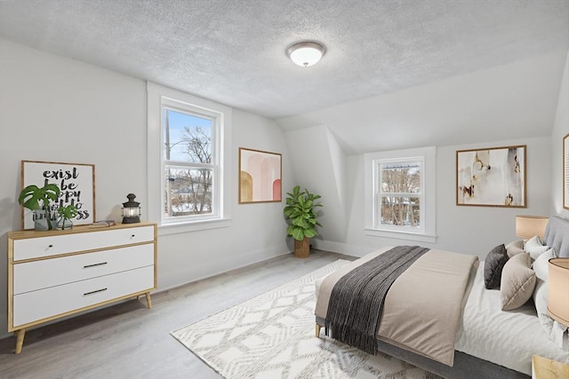 bedroom featuring lofted ceiling, hardwood / wood-style floors, and a textured ceiling