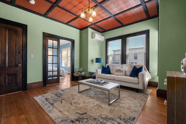 living area with a wall unit AC, light wood-type flooring, plenty of natural light, and baseboards