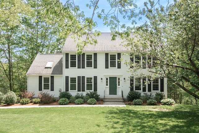 colonial home with a front yard and roof with shingles
