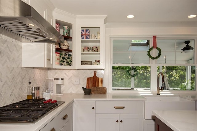 kitchen with wall chimney exhaust hood, stainless steel gas cooktop, white cabinetry, and backsplash