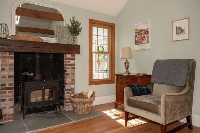 living area with wood finished floors, a wood stove, lofted ceiling, and plenty of natural light