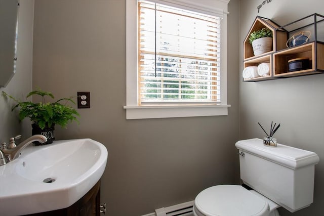 half bath with a sink, toilet, and baseboard heating
