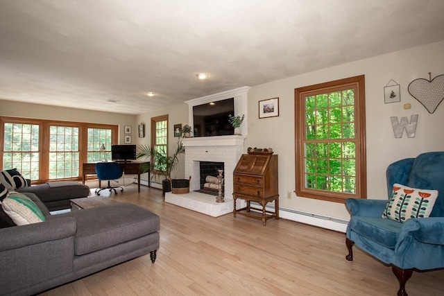 living room with light wood-style flooring, a fireplace, a baseboard heating unit, and recessed lighting