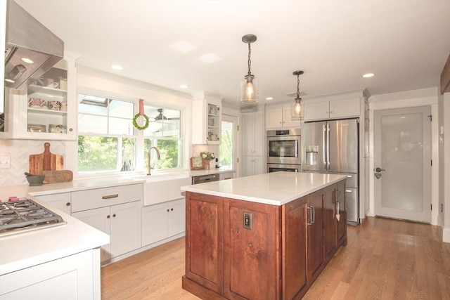 kitchen with appliances with stainless steel finishes, a sink, light wood finished floors, light countertops, and recessed lighting