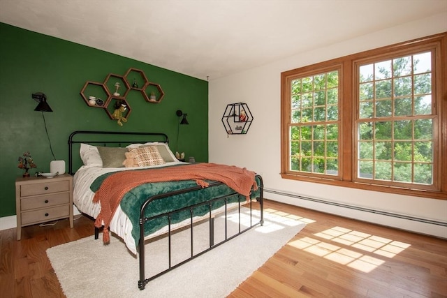 bedroom with baseboard heating, wood finished floors, and baseboards