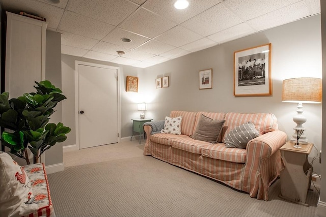 living area featuring carpet flooring, baseboards, and a drop ceiling