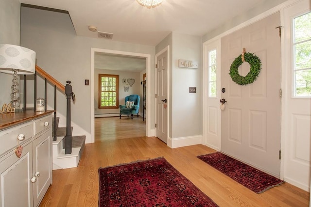 entryway featuring stairway, light wood-style floors, healthy amount of natural light, and baseboards