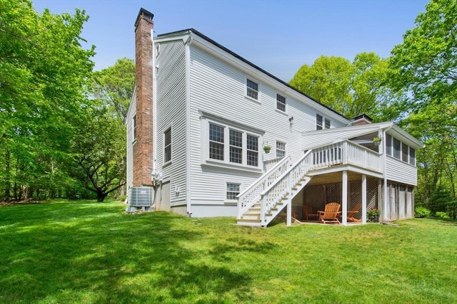 back of property with a chimney, stairway, a deck, and a lawn