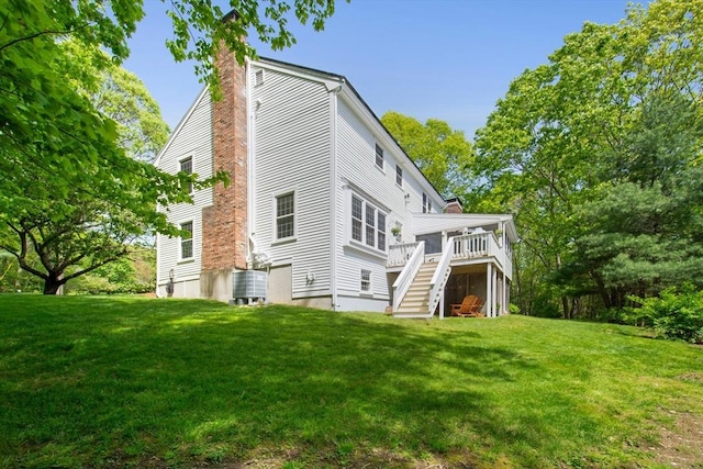 back of house featuring a chimney, stairway, a yard, and a deck