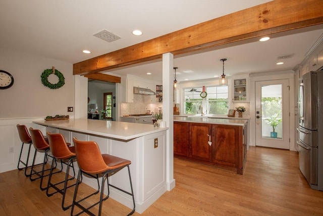 kitchen with freestanding refrigerator, light wood-style flooring, recessed lighting, beamed ceiling, and a peninsula