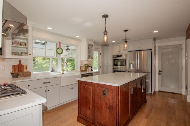 kitchen featuring stainless steel appliances, a sink, light countertops, light wood-style floors, and recessed lighting
