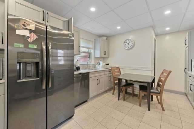 kitchen featuring a paneled ceiling, sink, stainless steel refrigerator with ice dispenser, and black dishwasher