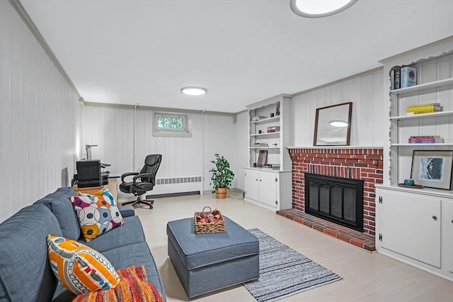 living room with radiator, a brick fireplace, wood finished floors, and ornamental molding