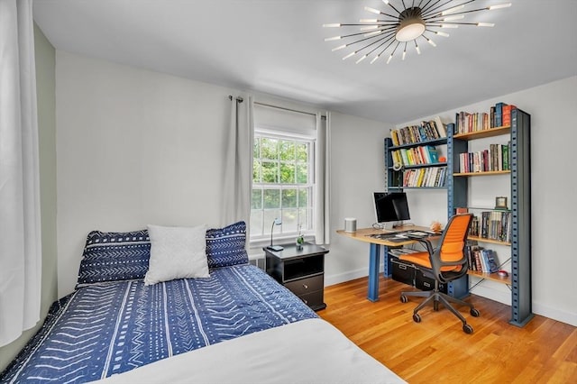 bedroom with wood finished floors, baseboards, a chandelier, and an office area