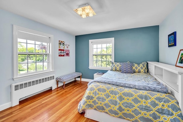 bedroom featuring radiator, wood finished floors, and baseboards