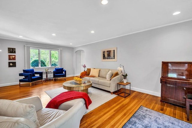 living area featuring arched walkways, wood finished floors, crown molding, recessed lighting, and baseboards