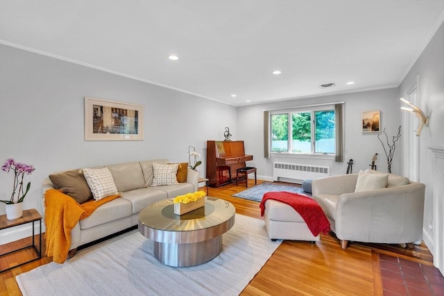 living area with radiator, ornamental molding, wood finished floors, recessed lighting, and baseboards
