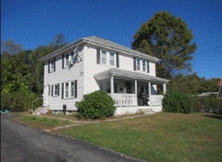 colonial house featuring covered porch and a front lawn