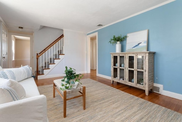 living room with stairs, wood finished floors, visible vents, and baseboards