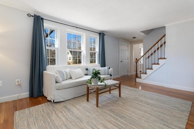 living room featuring stairs, baseboards, and wood finished floors