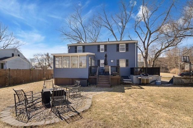 back of property with a wooden deck, a sunroom, a yard, and fence