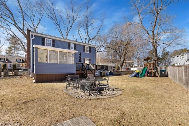 rear view of property featuring a fenced backyard, a playground, a yard, a sunroom, and a chimney