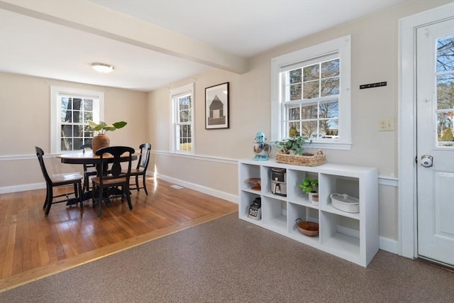 dining room with beam ceiling, wood finished floors, and baseboards