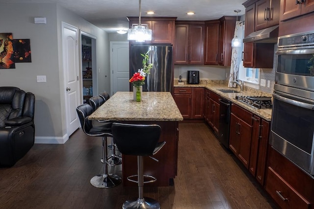 84 Murray Cir, Stoughton, MA 02072 - kitchen with stainless steel appliances, dark wood-style flooring, a kitchen breakfast bar, under cabinet range hood, and light stone counters