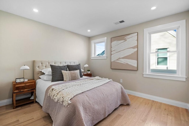 bedroom featuring light wood finished floors, visible vents, and baseboards