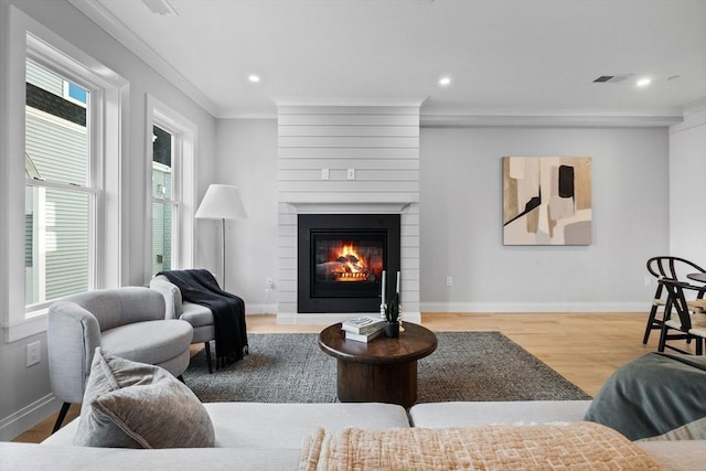 living room featuring a large fireplace, ornamental molding, recessed lighting, wood finished floors, and baseboards