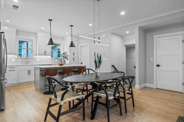 dining room featuring visible vents, baseboards, light wood-style floors, crown molding, and recessed lighting