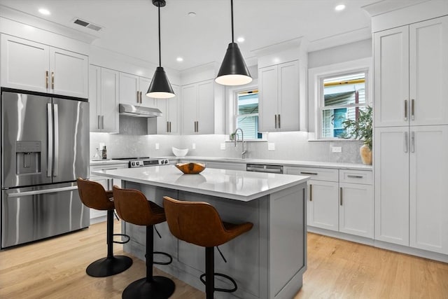 kitchen with a kitchen bar, visible vents, a center island, appliances with stainless steel finishes, and under cabinet range hood