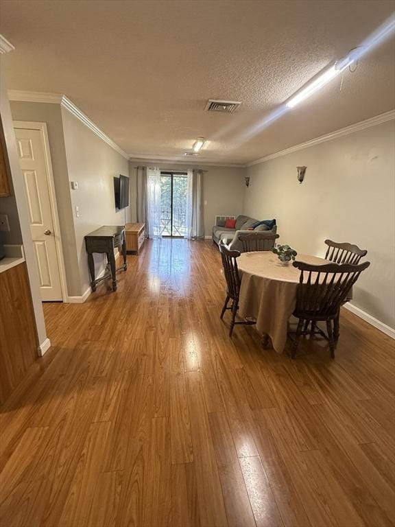 dining room featuring hardwood / wood-style floors, crown molding, and a textured ceiling