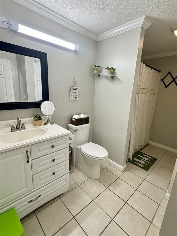 bathroom with a textured ceiling, tile patterned floors, vanity, and crown molding