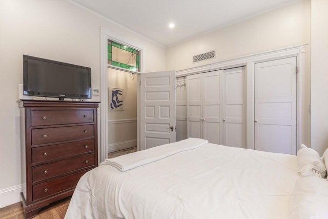 bedroom with crown molding, a closet, and light hardwood / wood-style flooring