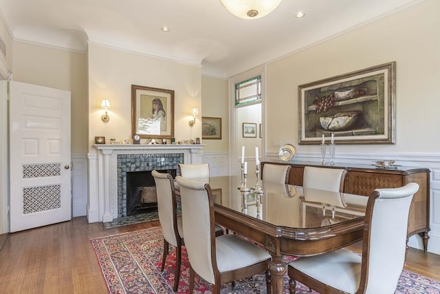 dining area with a fireplace, ornamental molding, and dark wood-type flooring