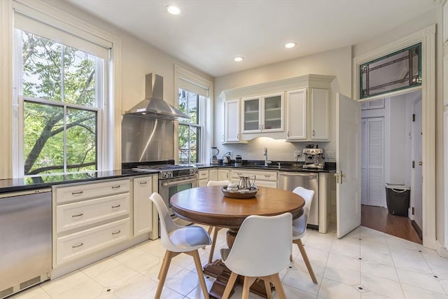 kitchen with white cabinets, appliances with stainless steel finishes, plenty of natural light, and wall chimney exhaust hood