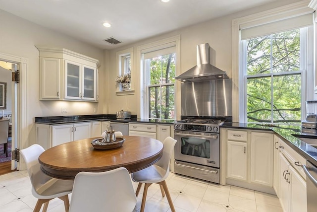 kitchen with white cabinetry, plenty of natural light, stainless steel appliances, and wall chimney range hood