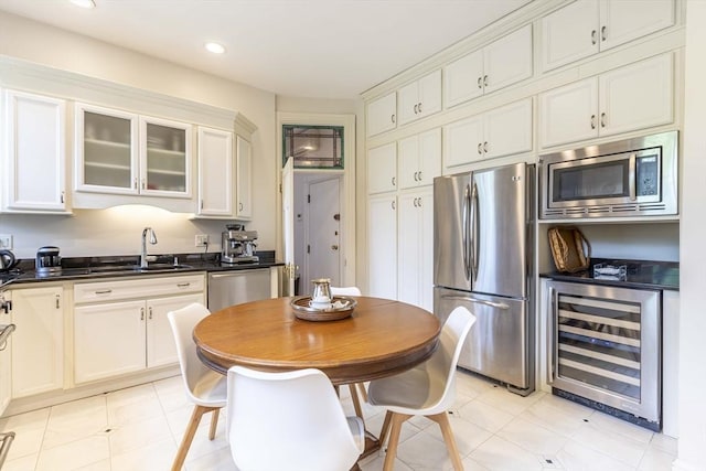 kitchen featuring white cabinetry, sink, beverage cooler, light tile patterned flooring, and appliances with stainless steel finishes