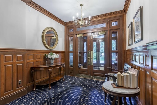 entrance foyer with a chandelier, french doors, and crown molding