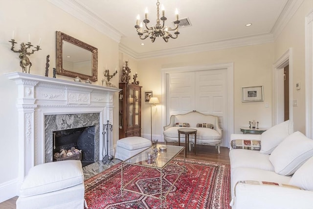 living room featuring a chandelier, wood-type flooring, ornamental molding, and a premium fireplace